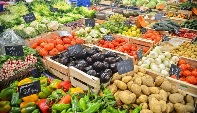A variety of vegetables in crates being sold at a market.